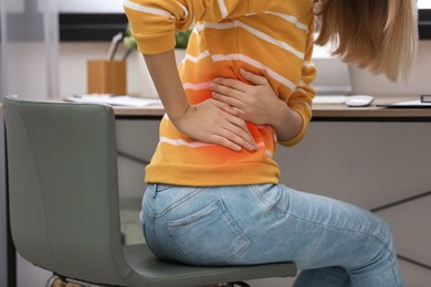 Image of Woman suffering from pain in lower back at workplace in office, closeup