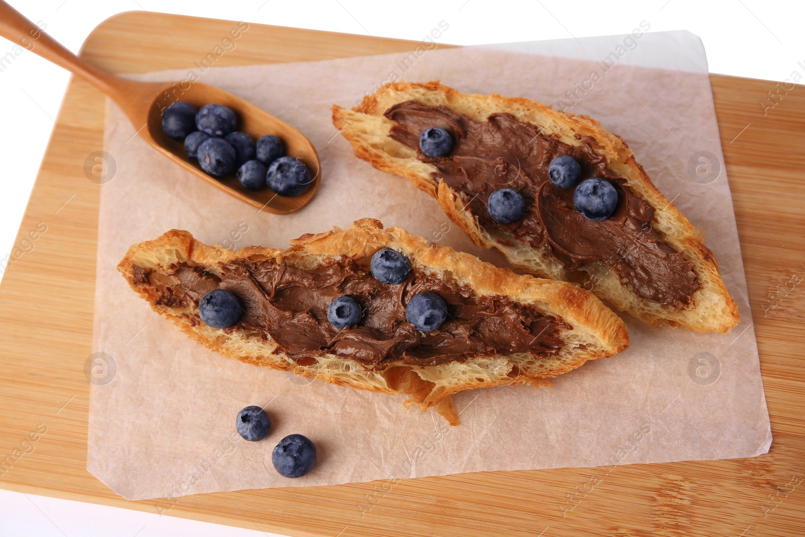 Photo of Tasty croissant with chocolate paste and blueberries on white background