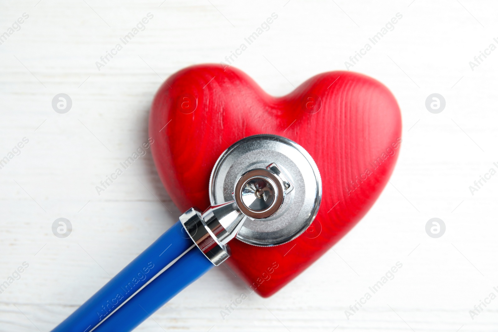 Photo of Stethoscope and red heart on wooden background, top view. Cardiology concept