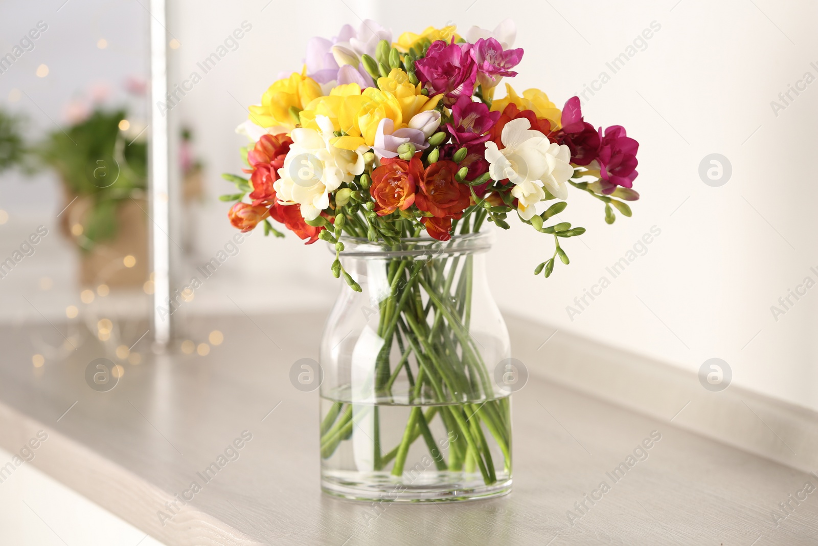 Photo of Beautiful spring bright freesia flowers in vase on table