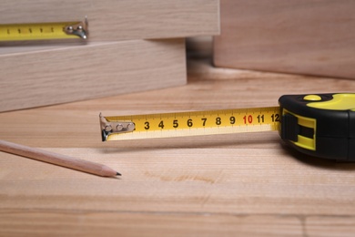 Photo of Tape measure and pencil on wooden surface, closeup