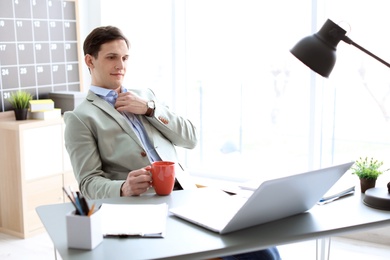 Photo of Portrait of confident young businessman drinking coffee at table