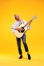 Photo of Happy hippie woman playing guitar on yellow background