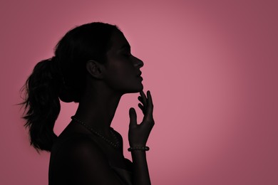 Silhouette of woman on pink background, profile portrait. Space for text