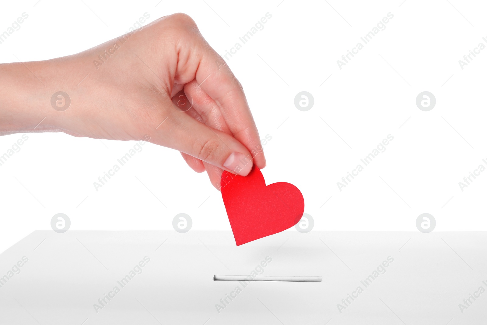 Photo of Woman putting red heart into slot of donation box against white background, closeup