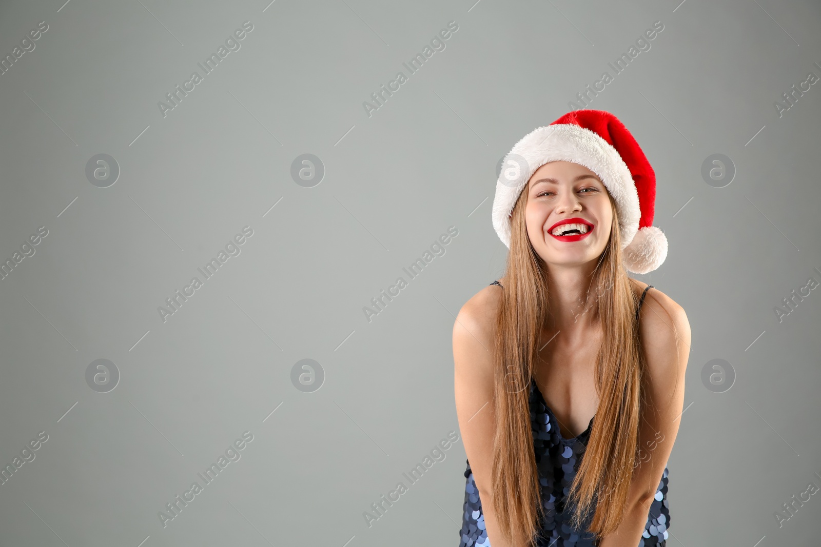 Photo of Young beautiful woman in Santa hat on grey background. Christmas celebration