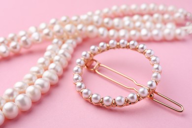 Photo of Elegant pearl hair clip and necklace on pink background, closeup