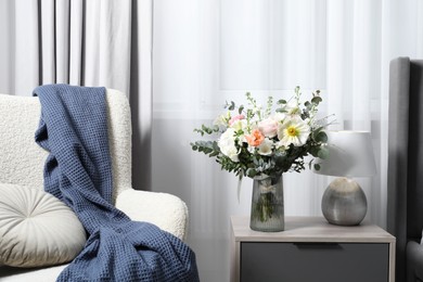 Bouquet of beautiful flowers near armchair indoors