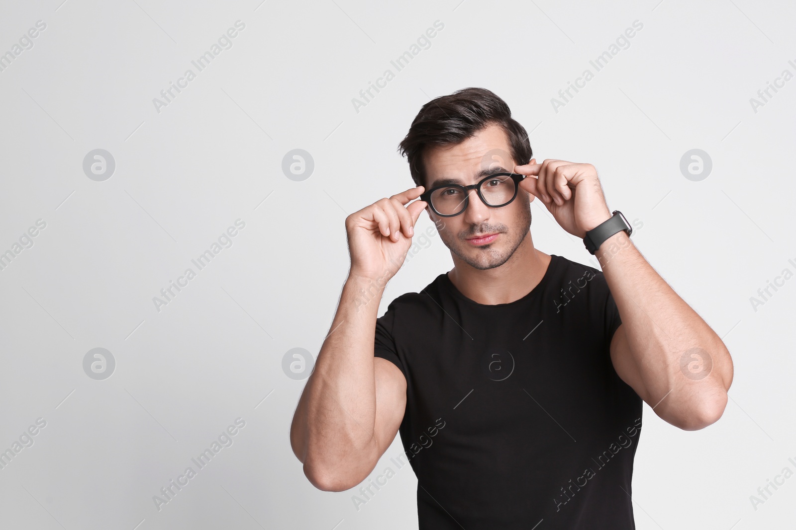 Photo of Portrait of handsome young man in black t-shirt with glasses on grey background. Space for text