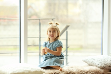 Photo of Cute little girl near window at home