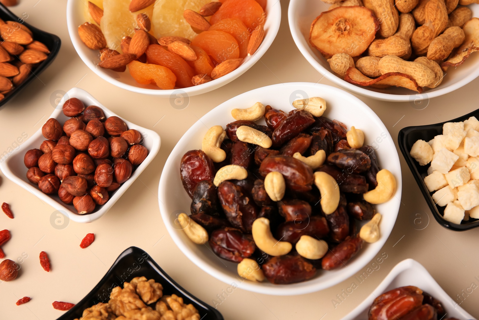 Photo of Bowls with dried fruits and nuts on beige background