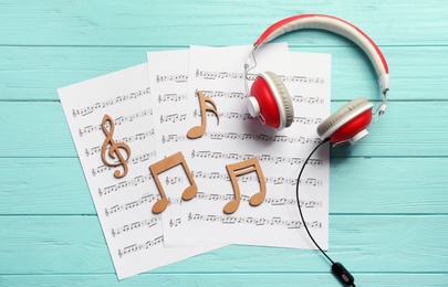 Flat lay composition with music notes and headphones on color wooden background