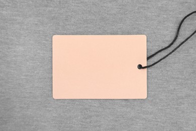 Photo of Cardboard tags on brown garment, top view. Space for text