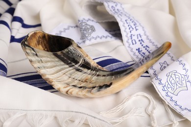 Photo of Shofar on tallit with text Blessed Are You, Lord Our God, King Of The Universe,
Who Has Sanctified Us With His Commandments, And Commanded Us To Enwrap Ourselves In Tzitzit. Rosh Hashanah holiday symbols