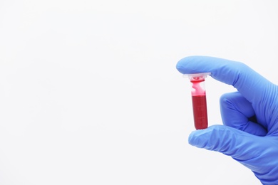 Scientist holding test tube with blood sample against light background. Space for text