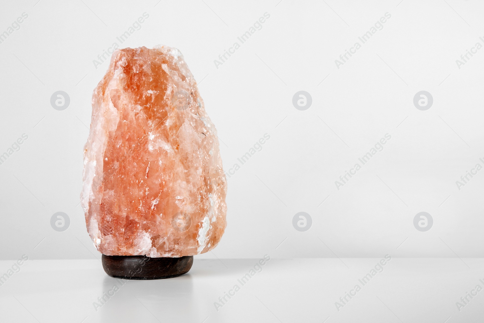 Photo of Himalayan salt lamp on table against light background