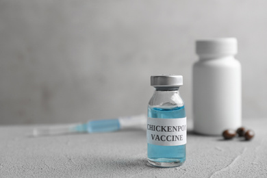Photo of Chickenpox vaccine and syringe on grey table, space for text. Varicella virus prevention
