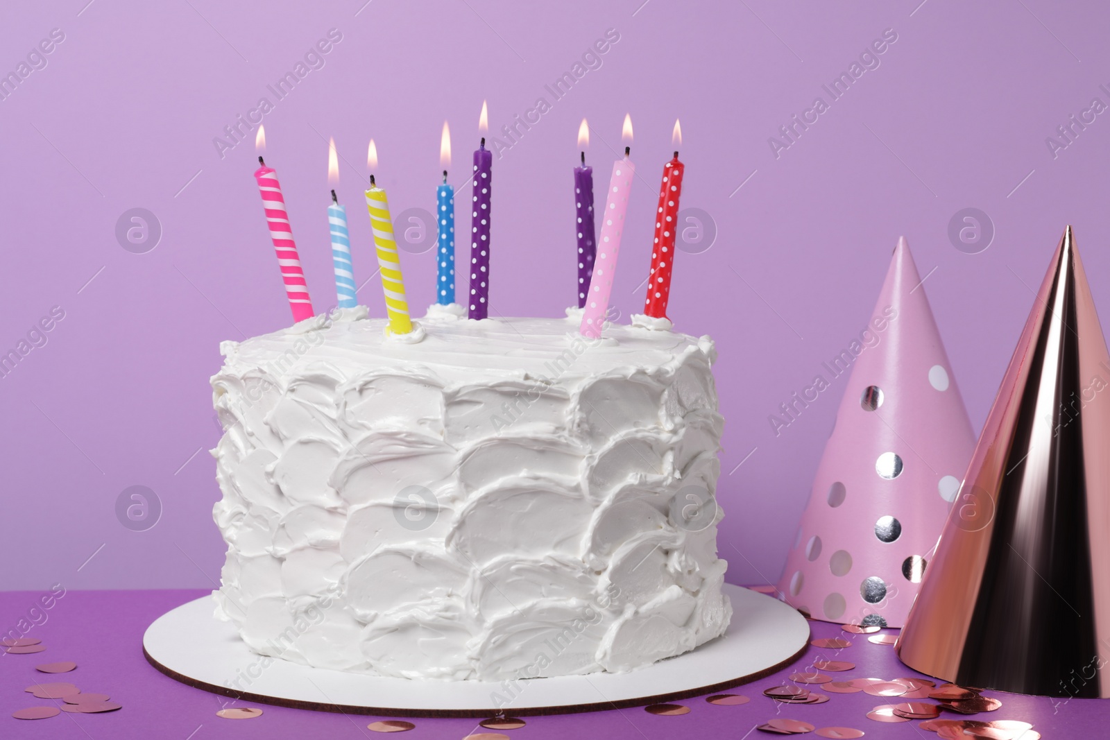 Photo of Delicious cake with burning candles and festive decor on purple background