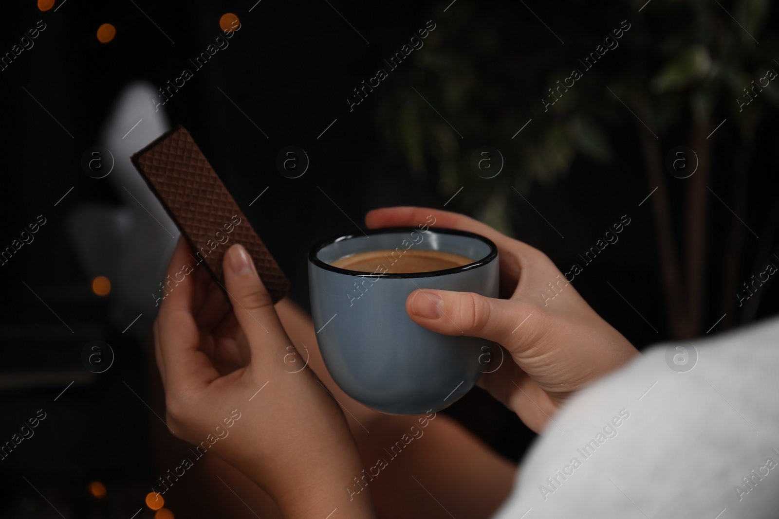 Photo of Woman with wafer and coffee on dark background, closeup. Early breakfast