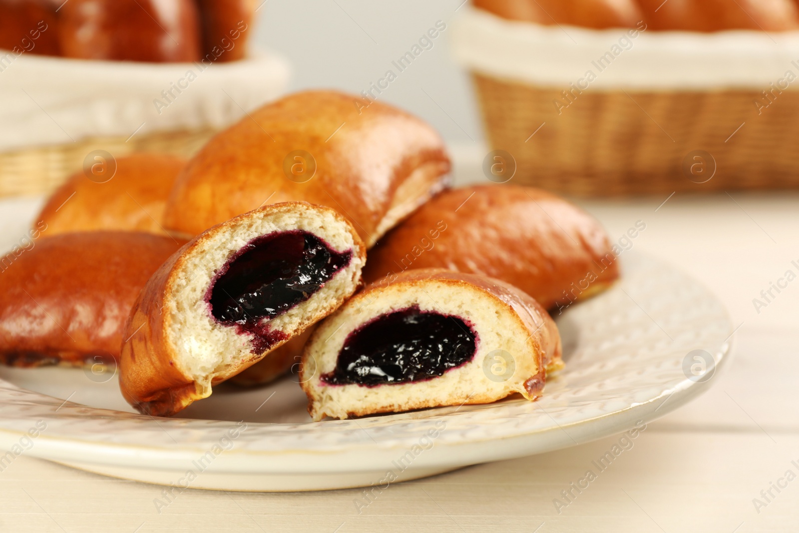 Photo of Delicious baked patties with jam on white wooden table, closeup