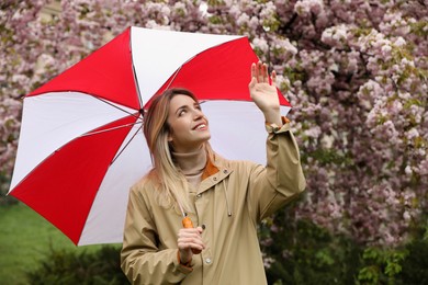Photo of Young woman with umbrella in park on spring day