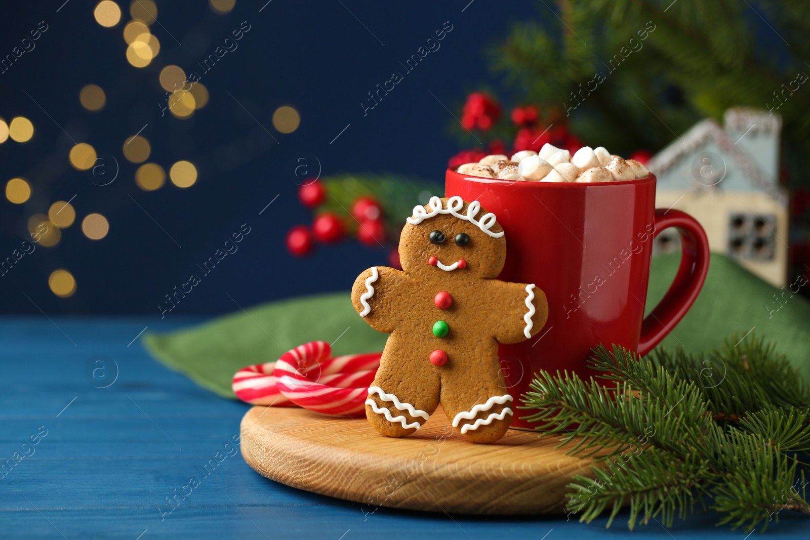 Photo of Tasty gingerbread man cookie and cocoa with marshmallows on blue wooden table. Space for text