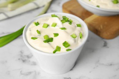 Photo of Fresh sour cream with onion on white marble table, closeup