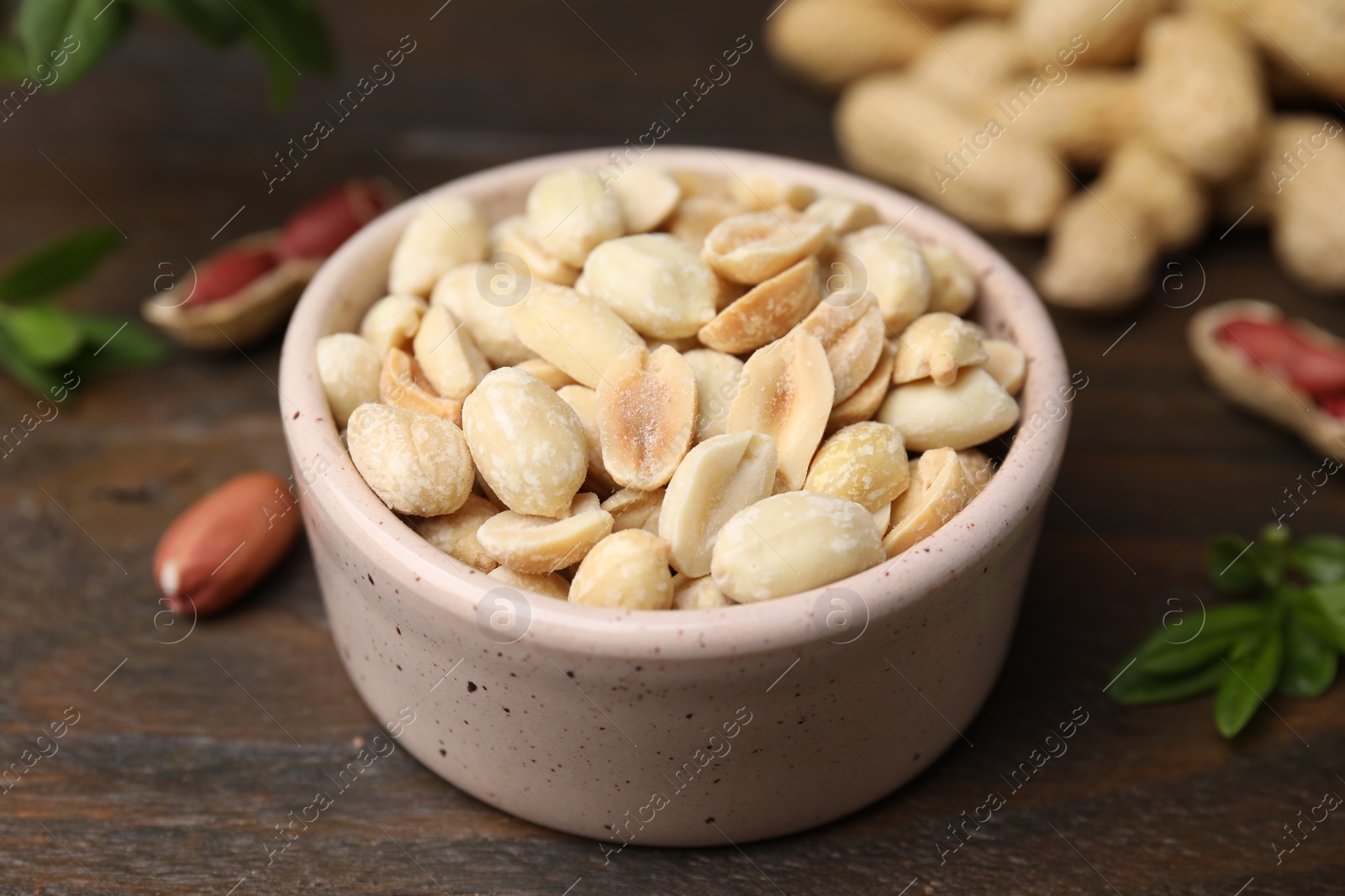 Photo of Fresh peeled peanuts in bowl on wooden table, closeup