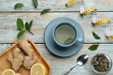 Flat lay composition with cup of diet herbal tea on light wooden background