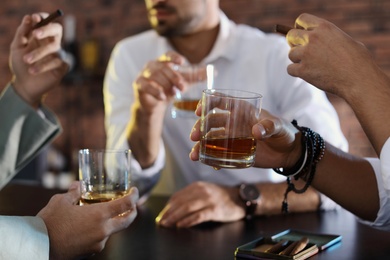 Photo of Group of friends drinking whiskey together in bar, closeup