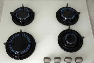 Photo of Gas burners with blue flame on modern stove, above view