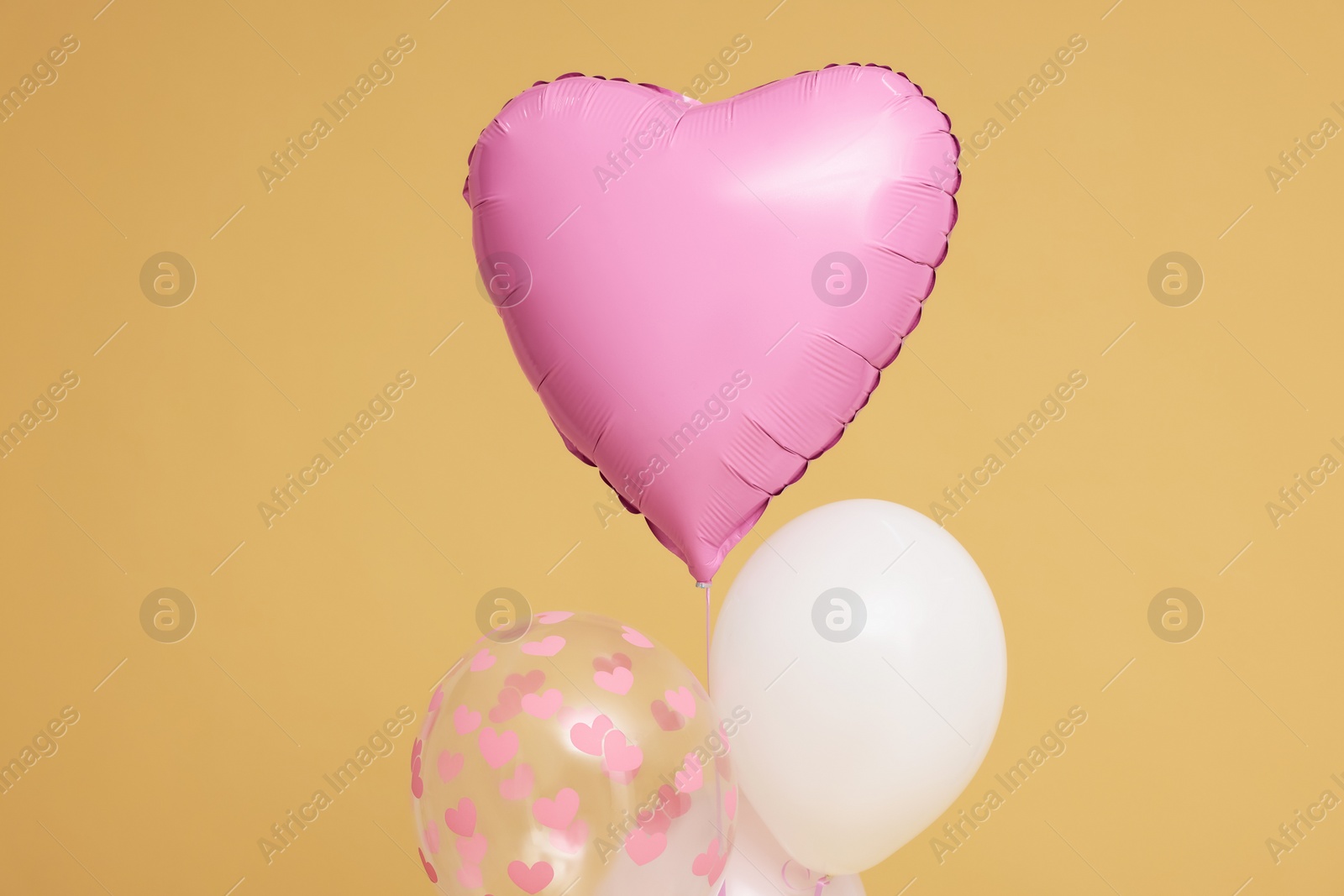 Photo of Bunch of heart and round shaped balloons for birthday party on beige background