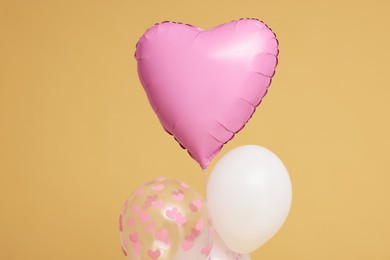 Photo of Bunch of heart and round shaped balloons for birthday party on beige background