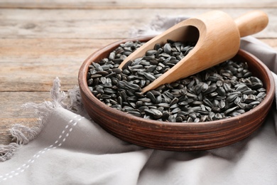 Bowl and scoop with sunflower seeds on table