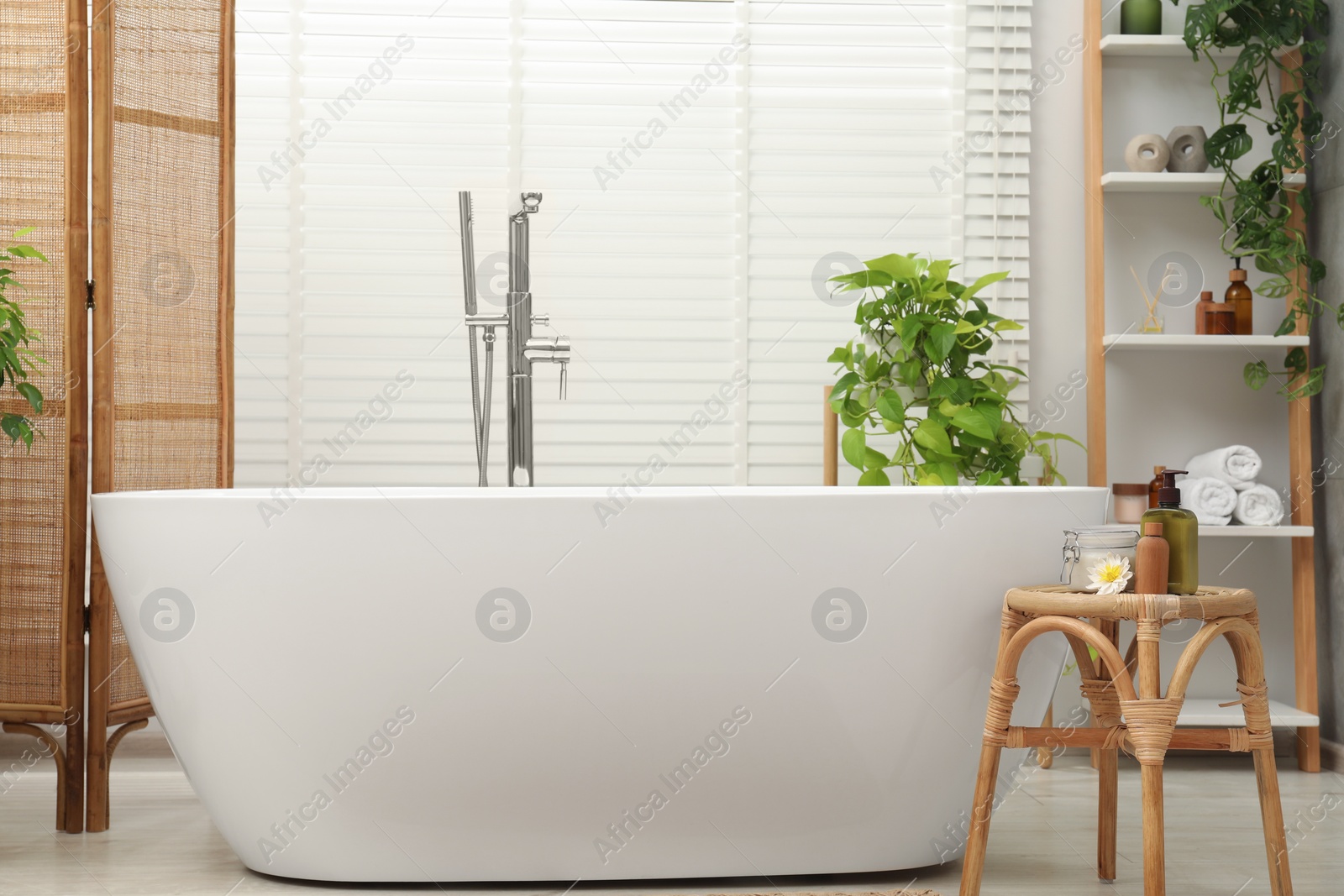 Photo of Spa day. Stylish bathroom interior with ceramic tub and green houseplants