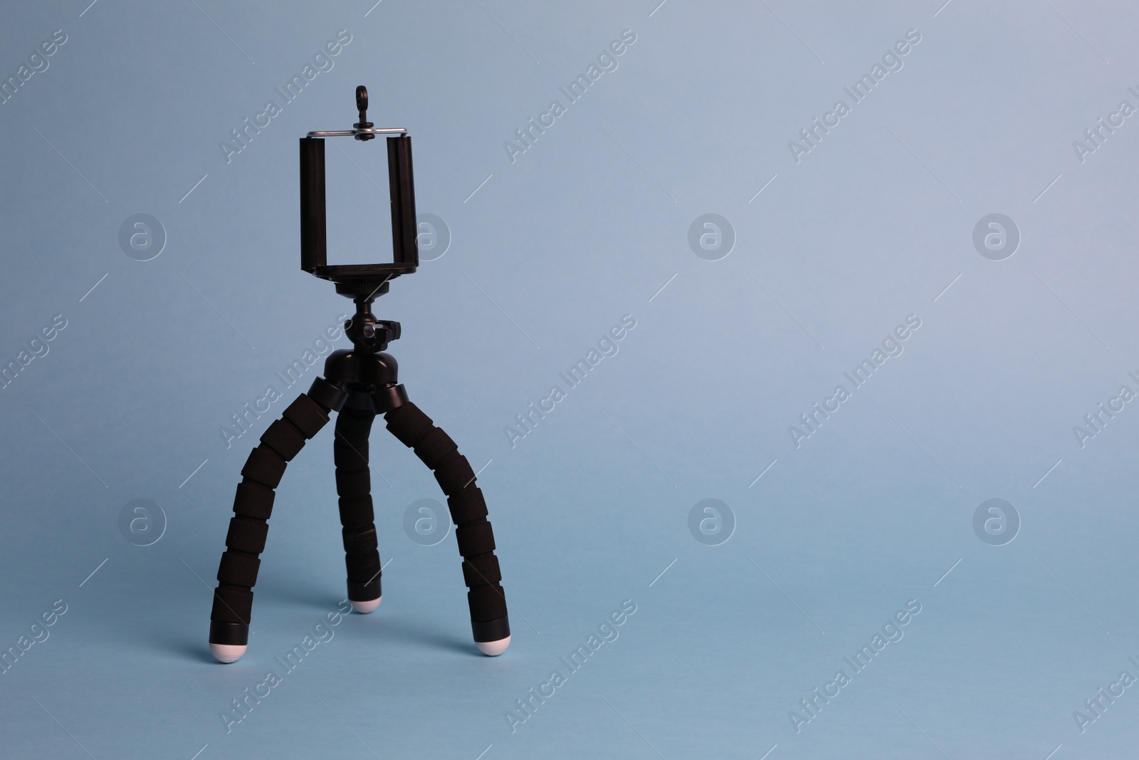 Photo of Modern stylish mobile tripod on light blue background. Space for text