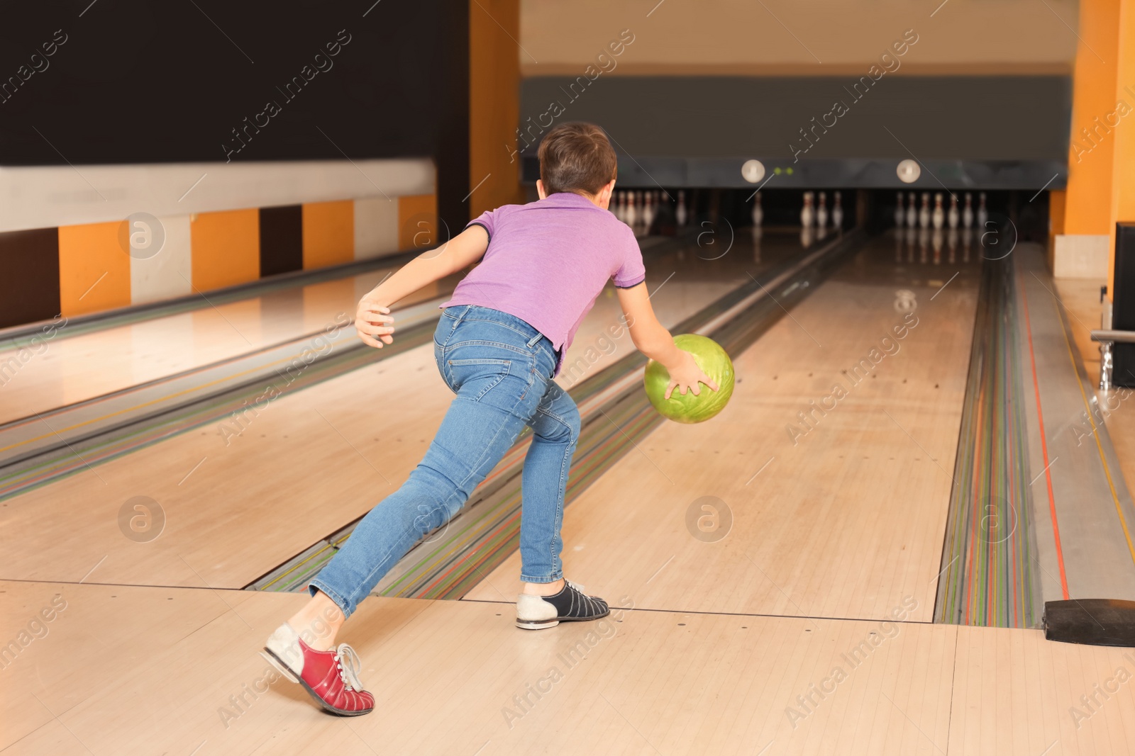 Photo of Preteen boy throwing ball at bowling club