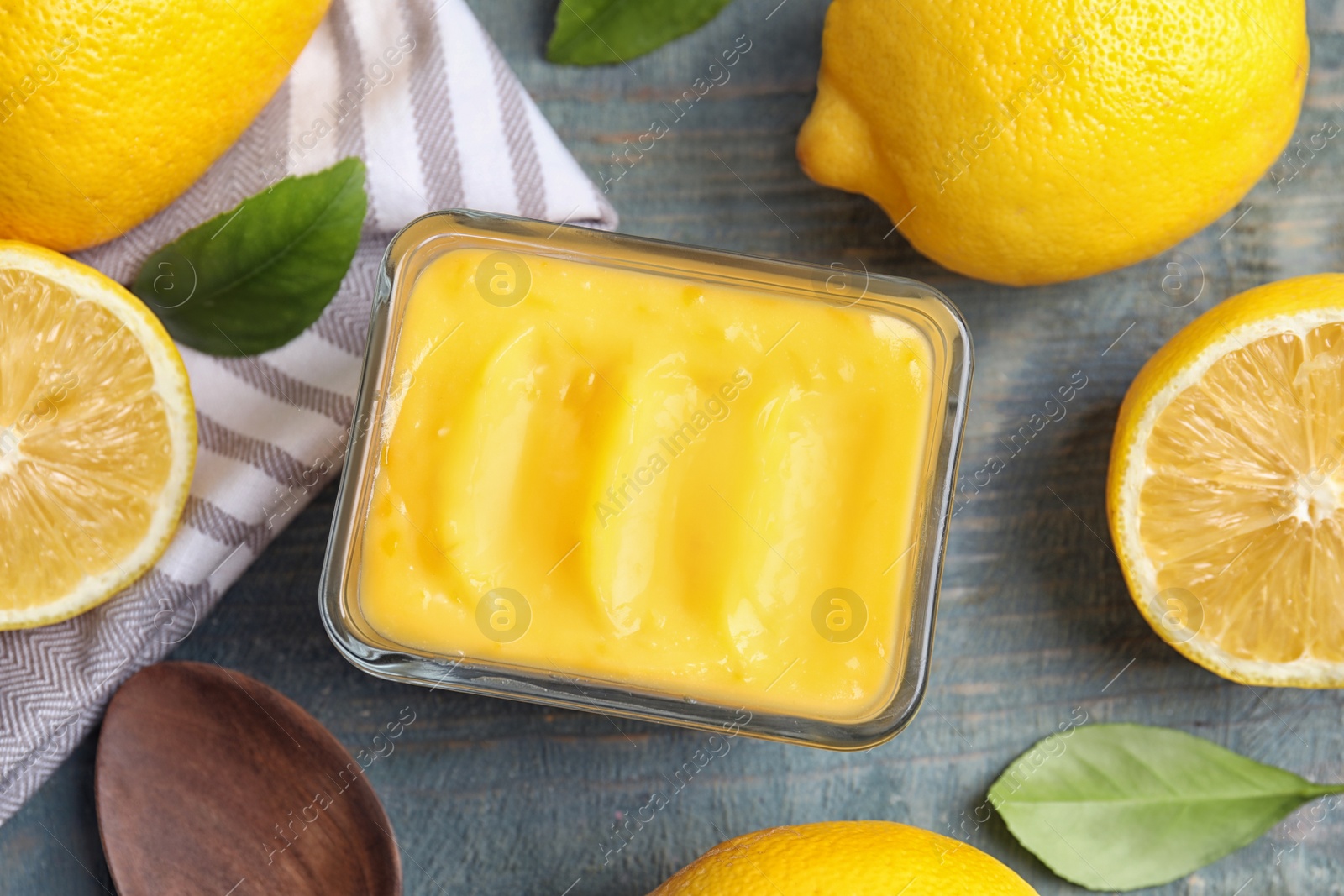 Photo of Delicious lemon curd in bowl on wooden table, flat lay