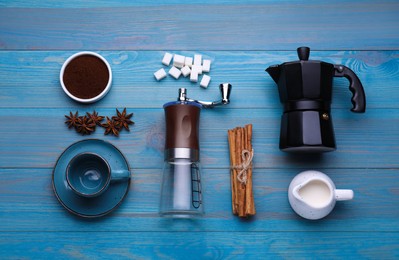 Flat lay composition with manual grinder and geyser coffee maker on light blue wooden background