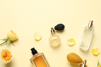 Photo of Flat lay composition with different perfume bottles on light yellow background, space for text