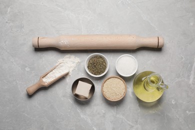 Photo of Cooking grissini. Different ingredients and utensils on grey marble table, flat lay