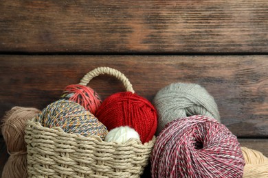 Soft woolen yarns on wooden table, flat lay. Space for text