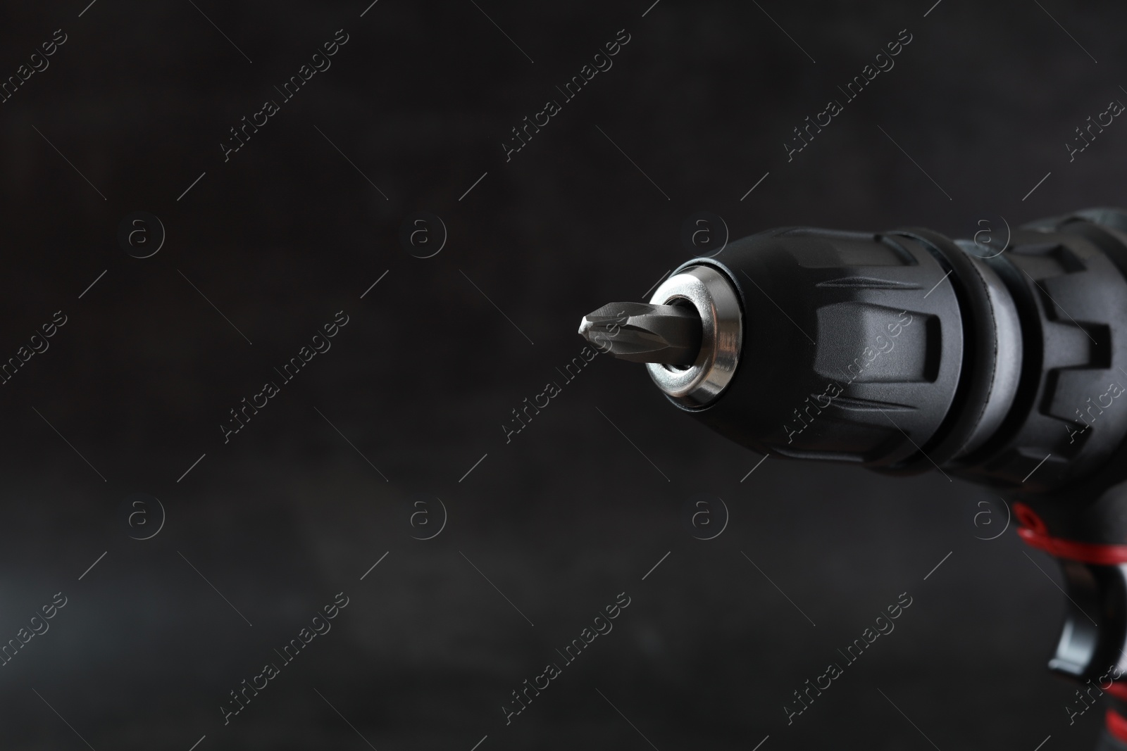 Photo of Modern electric screwdriver on dark grey background, closeup. Space for text