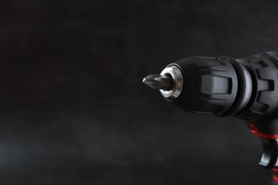 Modern electric screwdriver on dark grey background, closeup. Space for text