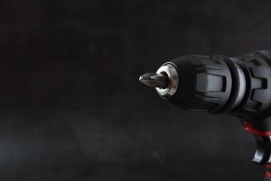 Photo of Modern electric screwdriver on dark grey background, closeup. Space for text