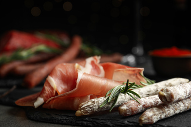 Delicious sausages and prosciutto on table, closeup