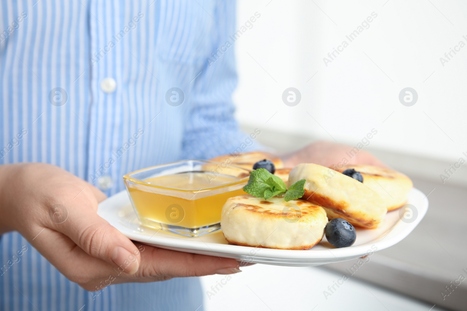 Photo of Woman with plate of delicious cottage cheese pancakes, closeup