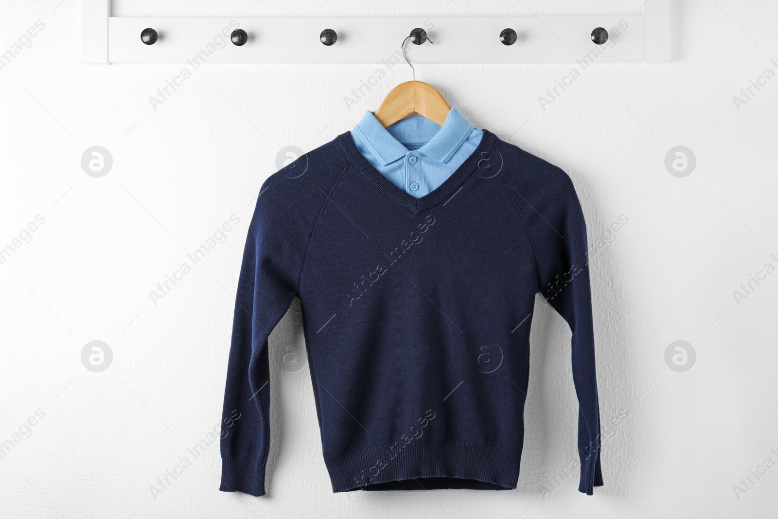 Photo of Shirt and jumper on hanger indoors. School uniform