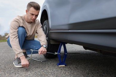 Young man changing tire of car on roadside