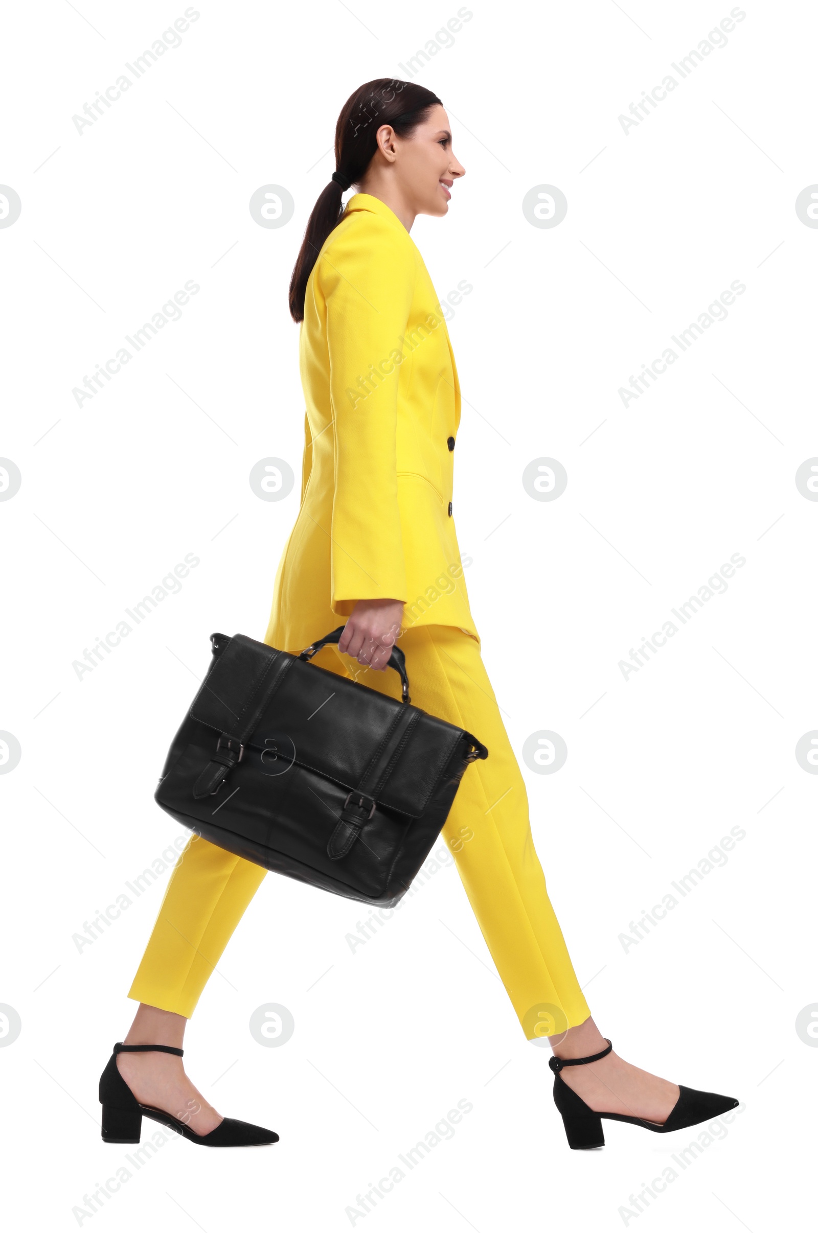 Photo of Beautiful businesswoman in yellow suit with briefcase walking on white background